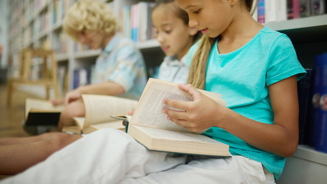 Girl leafing through book sitting with friends on floor